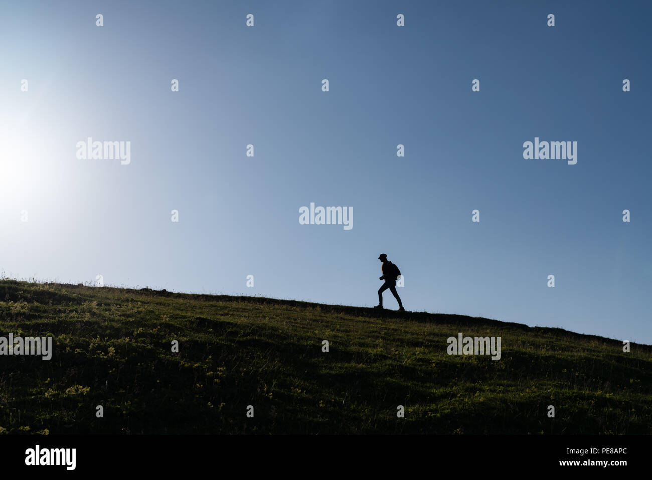 SIlhouette of a lonely woman walking at sunset on a hill. Stock Photo