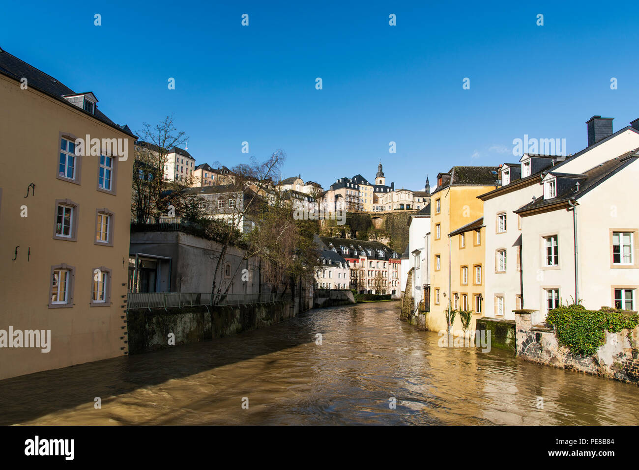 a view of the Alzette River as it passes through the Grund Quarter in Luxembourg City, Luxembourg, and the Ville Haute Quarter on the top, highlightin Stock Photo