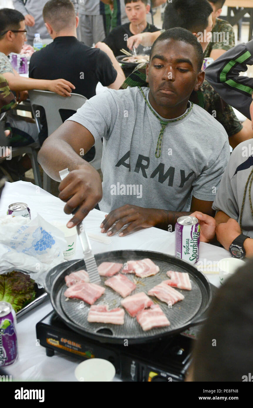 Pfc. Quinton Robinson, a combat engineer from Memphis, Tenn., assigned to Bravo Company, 8th Brigade Engineer Battalion, 2nd Armored Brigade Combat Team, 1st Cavalry Division, cooks a platter of meat for his newly-made Korean friends at a Korean barbecue-style dining facility located on a Republic of Korea Army base near Bucheon, South Korea, Sept. 30, 2015. (U.S. Army photo by Staff Sgt. John Healy, 2ABCT PAO, 1st Cavalry Division) Stock Photo