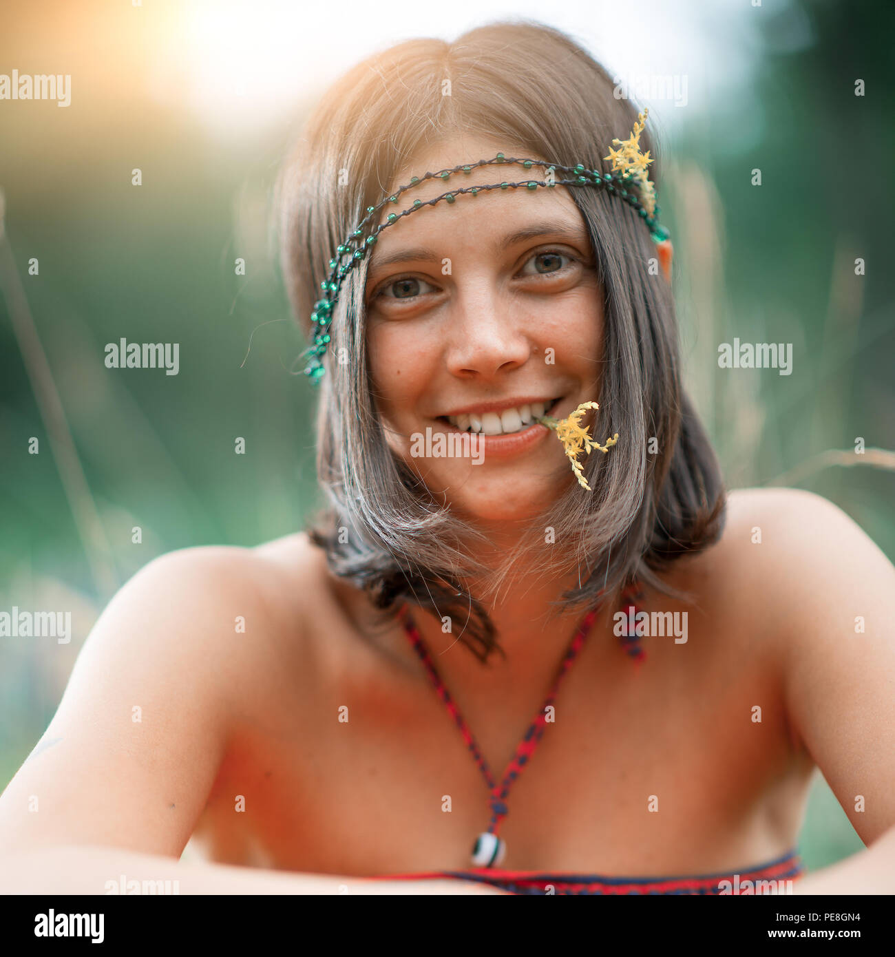 Portrait of a Woodstock Hippie style girl. With flower in the mouth. deliberately vintage photograph Stock Photo