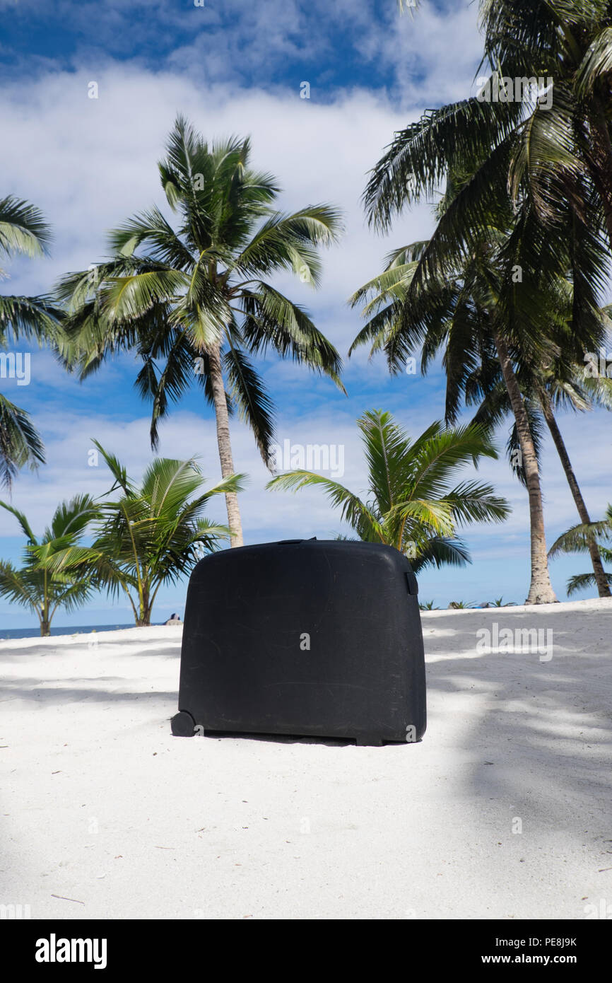 Old, well traveled scratched suitcase on tropical sandy beach with palm trees - Upolu Island, Western Samoa, South Pacific - portrait orientation Stock Photo
