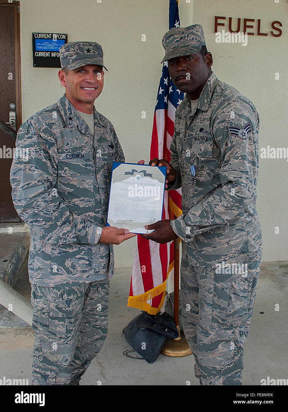 U.S. Air Force Brig. Gen. Barry Cornish, 18th Wing commander, hands Senior Airman Brian Moore, 18th Logistics Readiness Squadron fuels fixed facilities operator, an Air Force Achievement Medal citation Nov. 4, 2015, at Kadena Air Base, Japan. Moore and two other Airmen received the award for their role in saving the life of a fellow Airman. (U.S. Air Force photo by Airman 1st Class Corey M. Pettis) Stock Photo