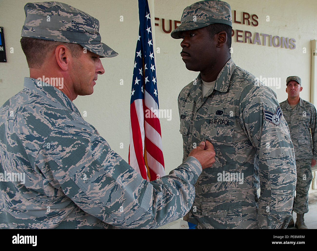 U.S. Air Force Brig. Gen. Barry Cornish, 18th Wing commander, pins the Air Force Achievement Medal on Senior Airman Brian Moore, 18th Logistics Readiness Squadron fuels fixed facilities operator, Nov. 4, 2015, at Kadena Air Base, Japan. Moore was instrumental in saving the life of a fellow Airman, who was attempting suicide. (U.S. Air Force photo by Airman 1st Class Corey M. Pettis) Stock Photo