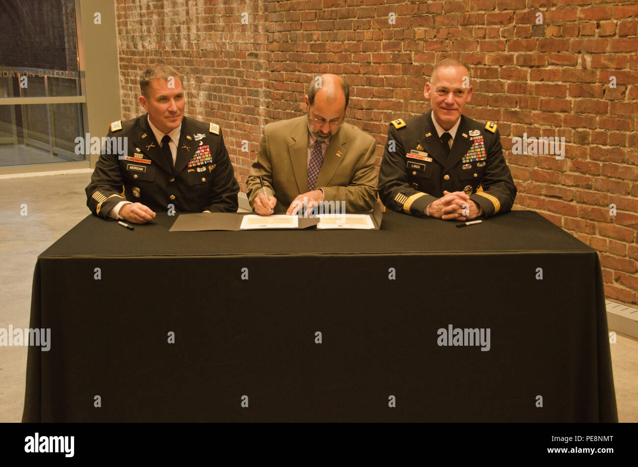 Col. Daniel S. Morgan, commander, Joint Base Lewis-McChord, left, Mark A. Pagano, chancellor, University of Washington-Tacoma, center, and Lt. Gen. Stephen R. Lanza, commanding general, I Corps, JBLM, right, come together to sign partnership resolutions at the UW-T, Oct. 29, 2015. Both JBLM and I Corps signed partnership resolutions with the UW-T agreeing to become a model university and military institutional partnership. (U.S. Army photo by Sgt. Jasmine Higgins, 28th Public Affairs Detachment) Stock Photo