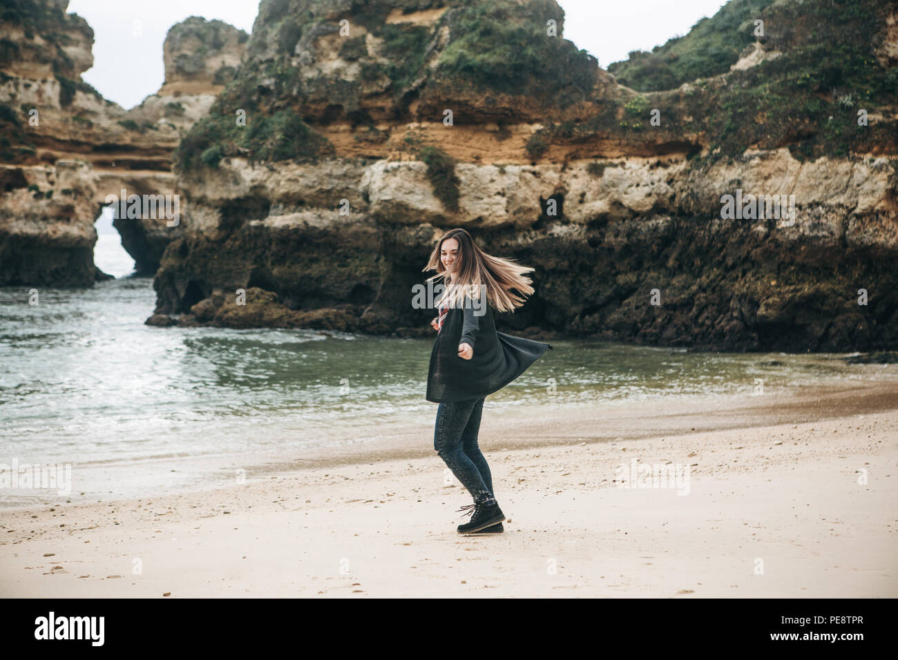 Young beautiful girl fooling around, whirling and having fun and enjoying life on the Atlantic coast in Portugal. Stock Photo