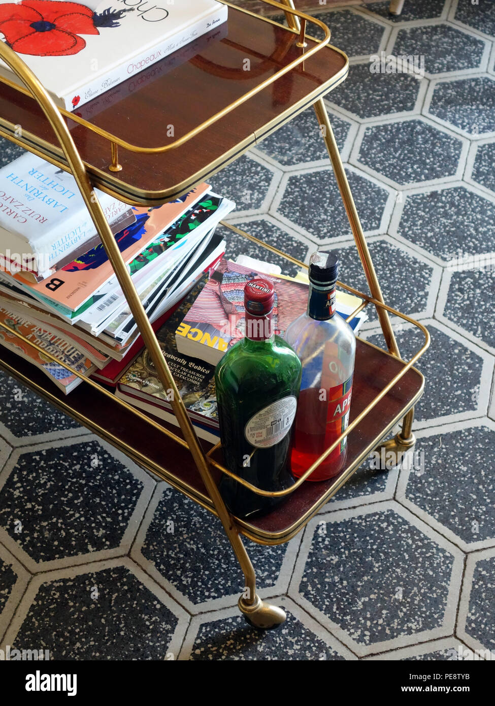 Closeup looking down at part of a Vintage Art Deco Trolley Mid Century with books and drinks on beautiful hexagon tiled floor in a large French house Stock Photo