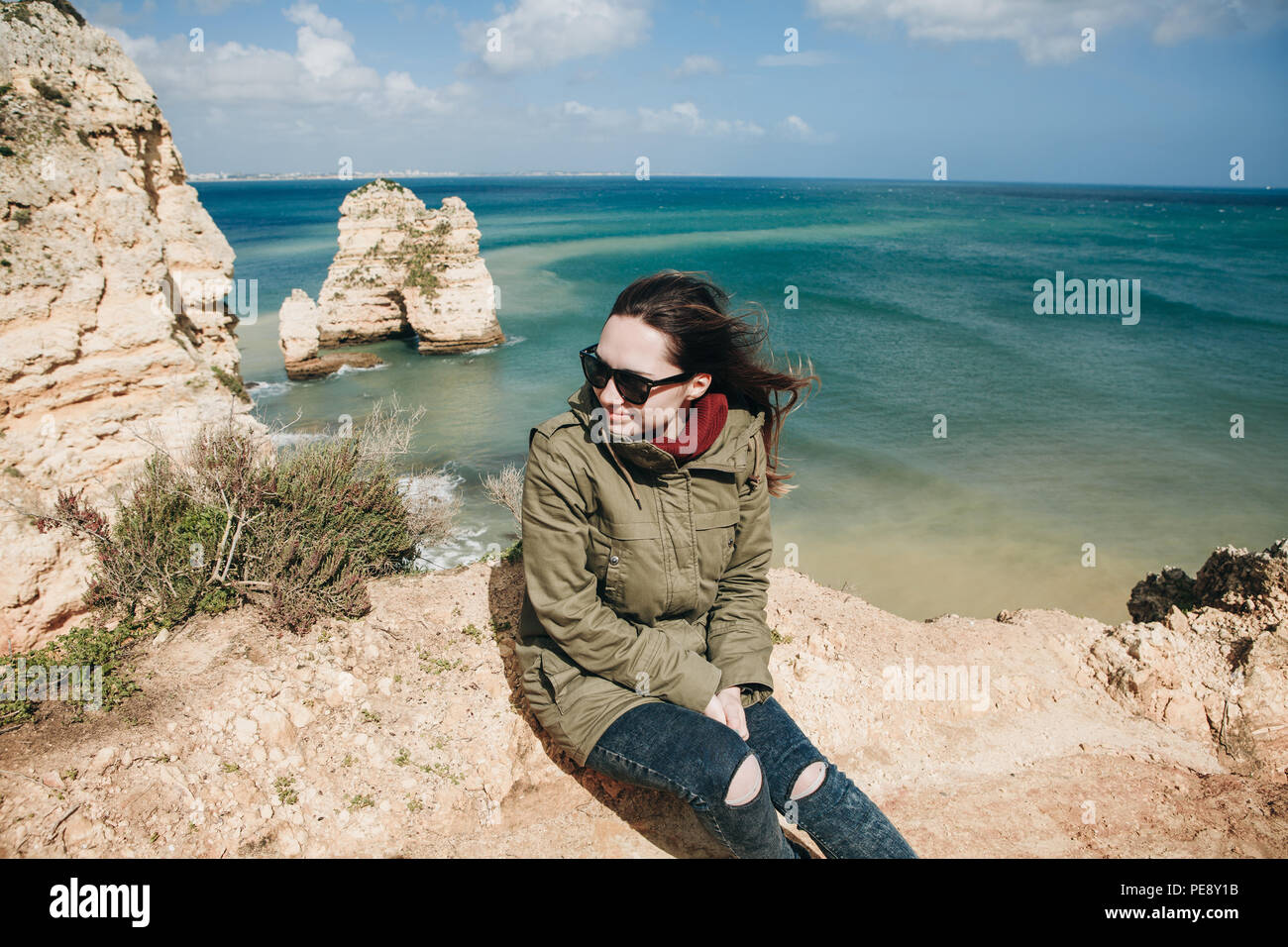 A young woman tourist enjoys the beautiful views of the Atlantic Ocean and the landscape off the coast in Portugal. Stock Photo