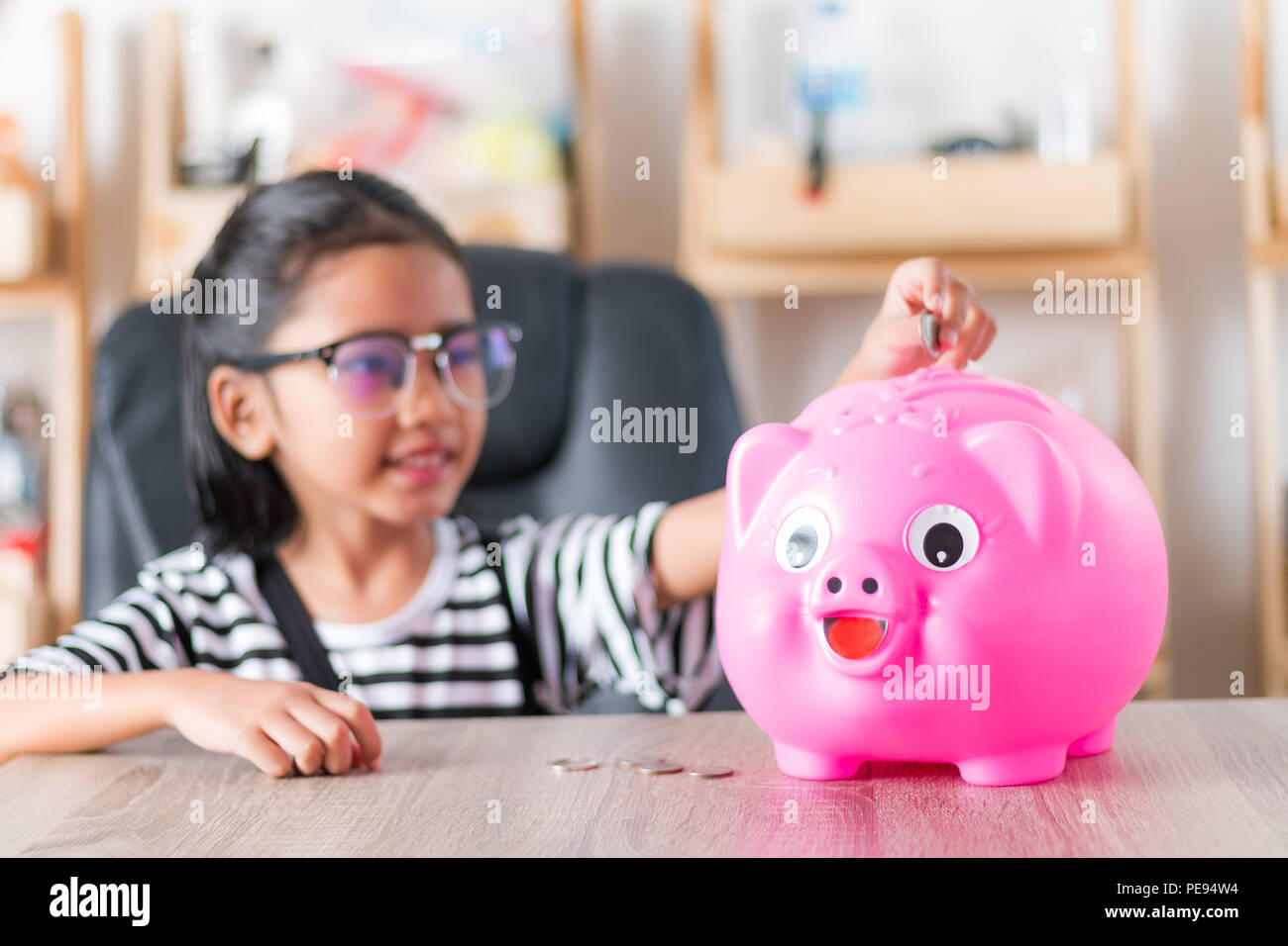 Asian little girl in putting coin in to piggy bank shallow depth of ...