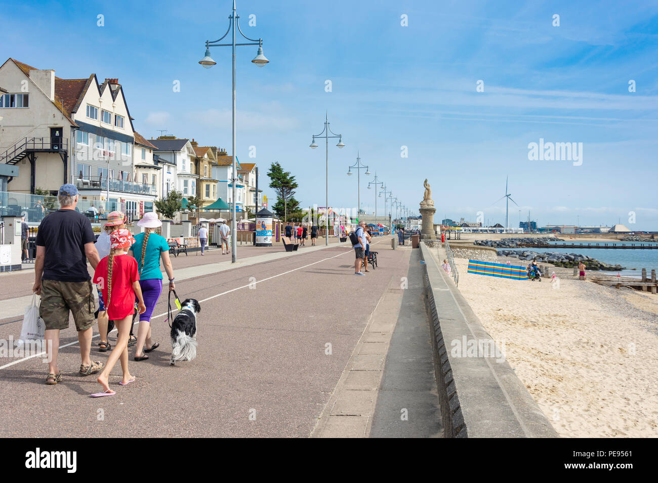 Family walking dog on beach promenade, Lowestoft, Suffolk, England