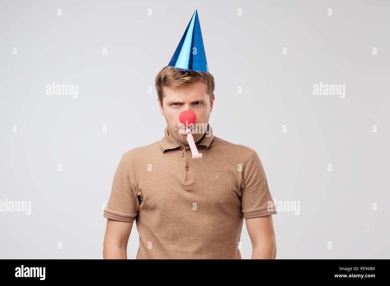 Funny mature man with red clown nose looking sadly at camera. Nobody came to his birthday party and he is offended. Stock Photo