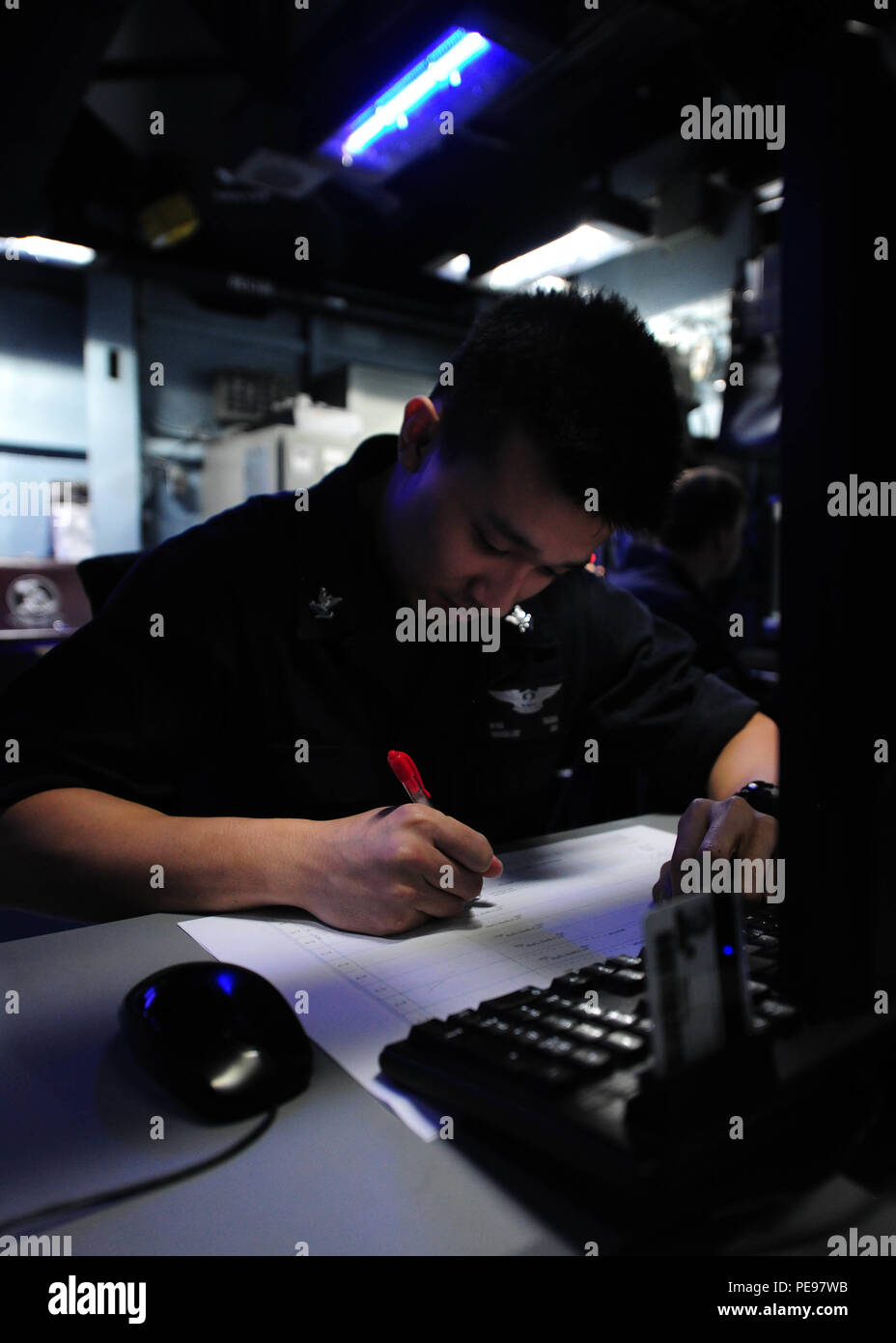 151112-N-PG340-066 PACIFIC OCEAN (Nov. 12, 2015) –Air Traffic Controller 2nd Class Minh Troung, from Phoenix, works on the hot sheet in carrier air traffic control center aboard the aircraft carrier USS Theodore Roosevelt (CVN 71). The hot sheet is a map of the area around the ship’s course that Theodore Roosevelt’s aircraft can fly. Theodore Roosevelt is operating in the U.S. 7th Fleet area of operations as part of a worldwide deployment en route to its new homeport in San Diego to complete a three-carrier homeport shift. (U.S. Navy Photo by Mass Communication Specialist 3rd Class Stephane Be Stock Photo