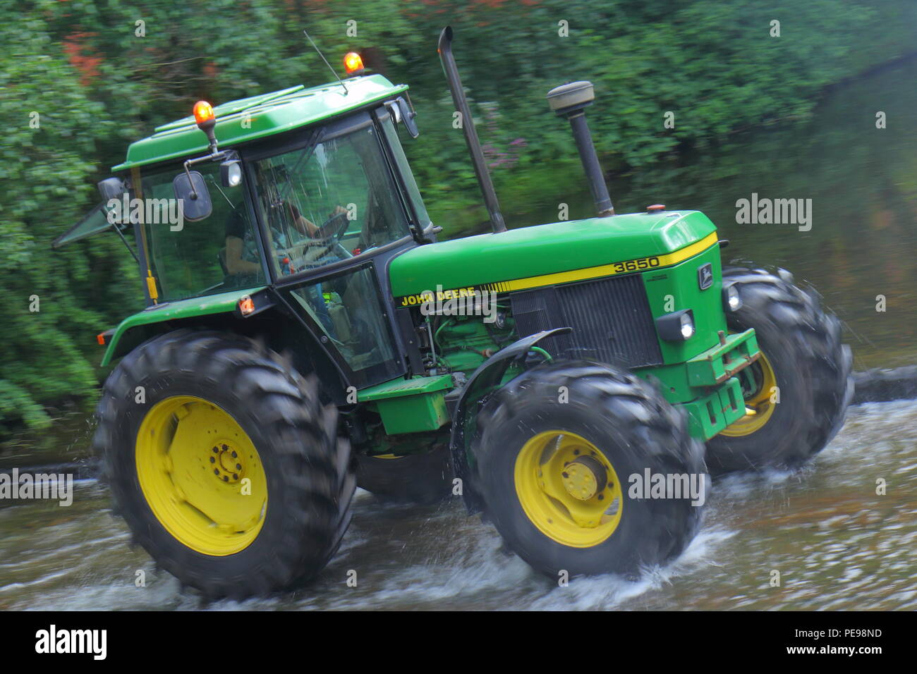 A John Deere tractor crosses the River Skell in Ripon with a convoy of