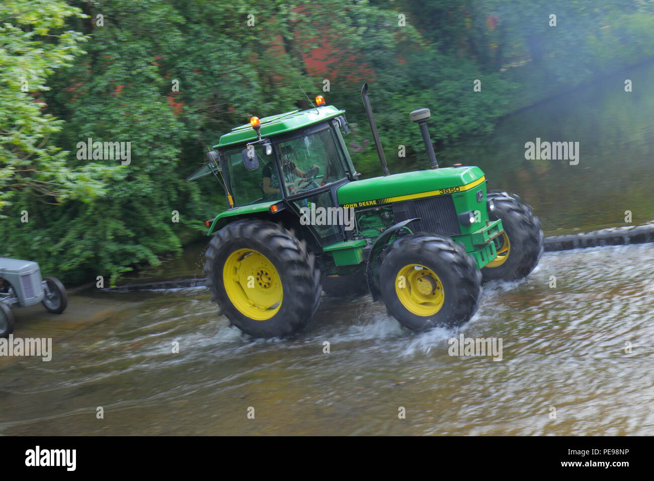 A John Deere tractor crosses the River Skell in Ripon with a convoy of