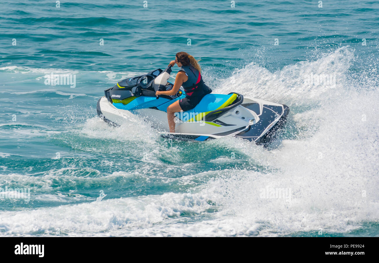 Woman riding a jet ski on the sea in Summer in the UK. Water sports.Jet ski. Jet skiing. Stock Photo