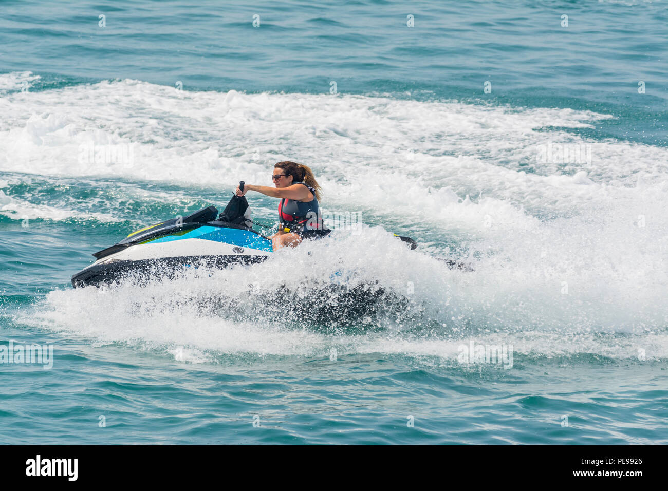 Woman riding a jet ski on the sea in Summer in the UK. Jet skiing. Jet ski. Stock Photo