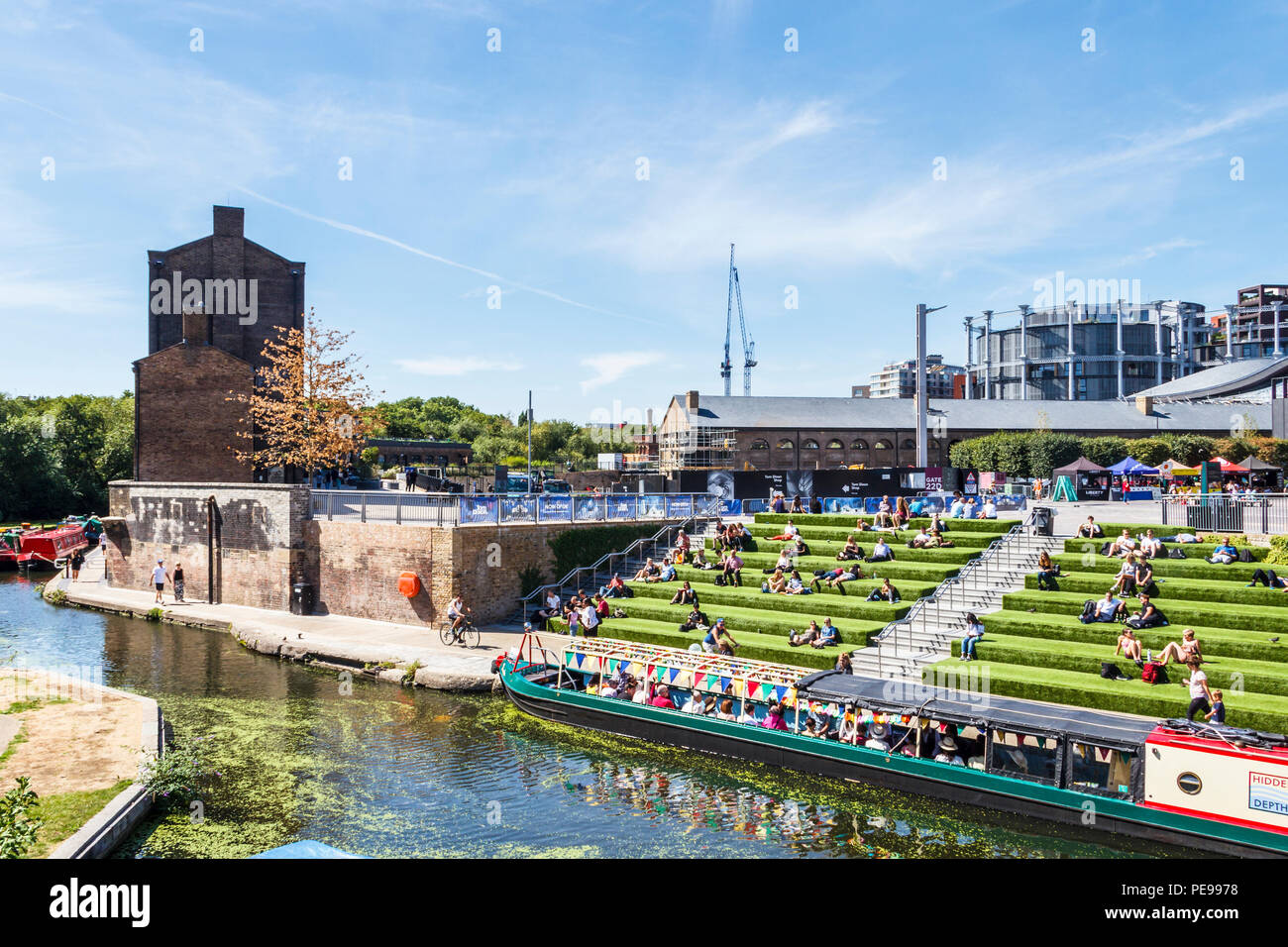 As temperatures rise, Londoners sun themselves on the steps by Regent's Canal at King's Cross, London, UK Stock Photo
