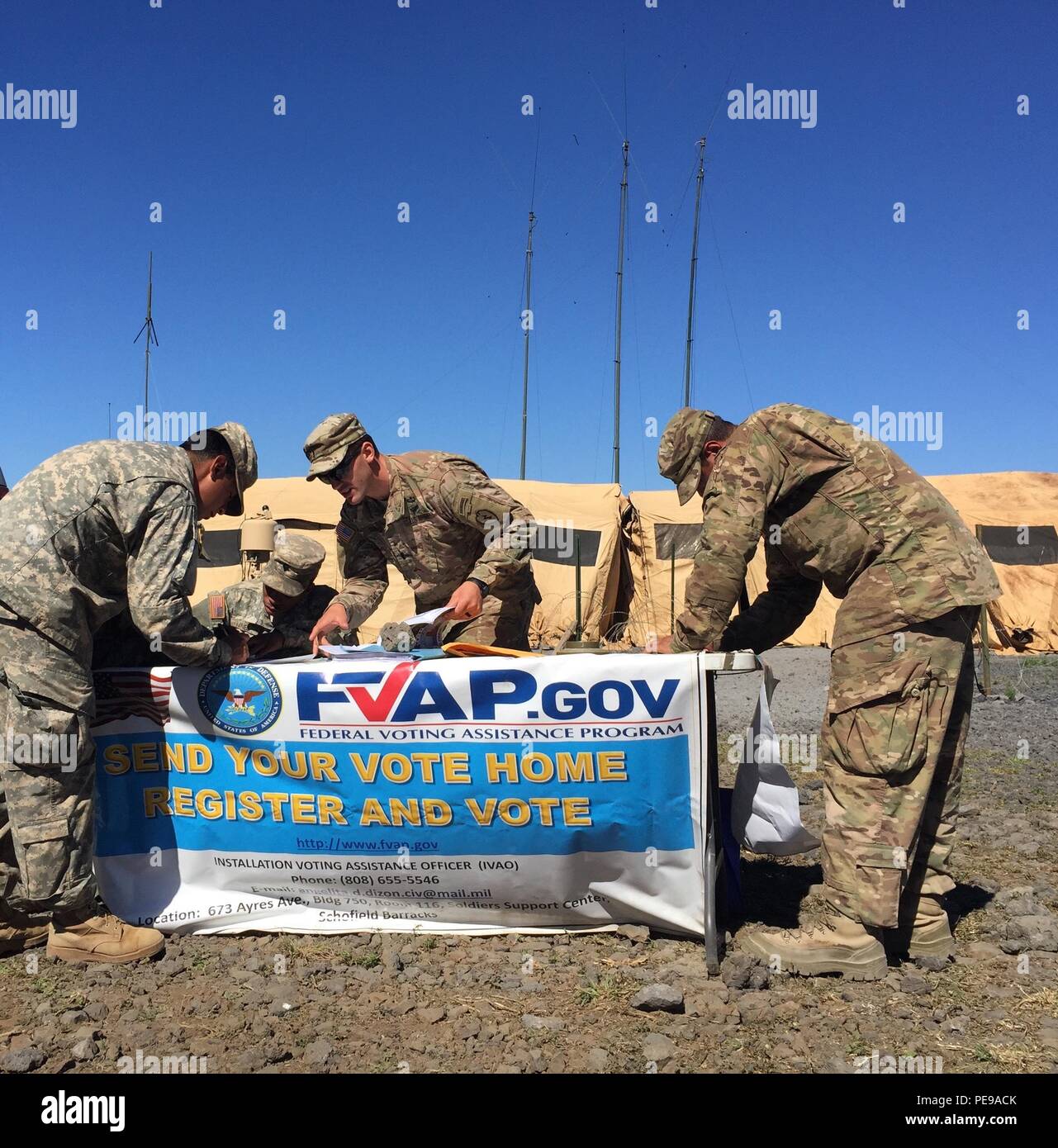 Voting Assistance Officer 1st Lt. Chase Cappo (middle back), assigned to 2nd Squadron 14th Cavalry Regiment, 2nd Brigade Combat Team, 25th Infantry Division, sets up a voter registration table with the FVAP banner at one of many training areas 2-14 CAV utilized at the Pohakuloa Training Area in Hawaii. (U.S. Army photo by 1st Lt. Edward Dieppa, Troop C, 2nd Squadron 14th Cavalry Regiment, 2nd Brigade Combat Team, 25th Infantry Division) Stock Photo