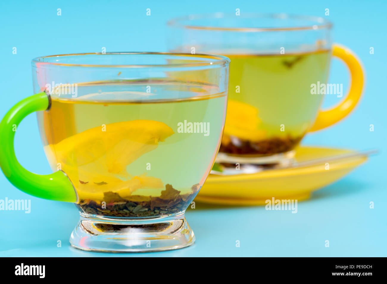 Close up on a glass cup of hot spicy tea with tea leaves over a blue background with a second cup behind Stock Photo