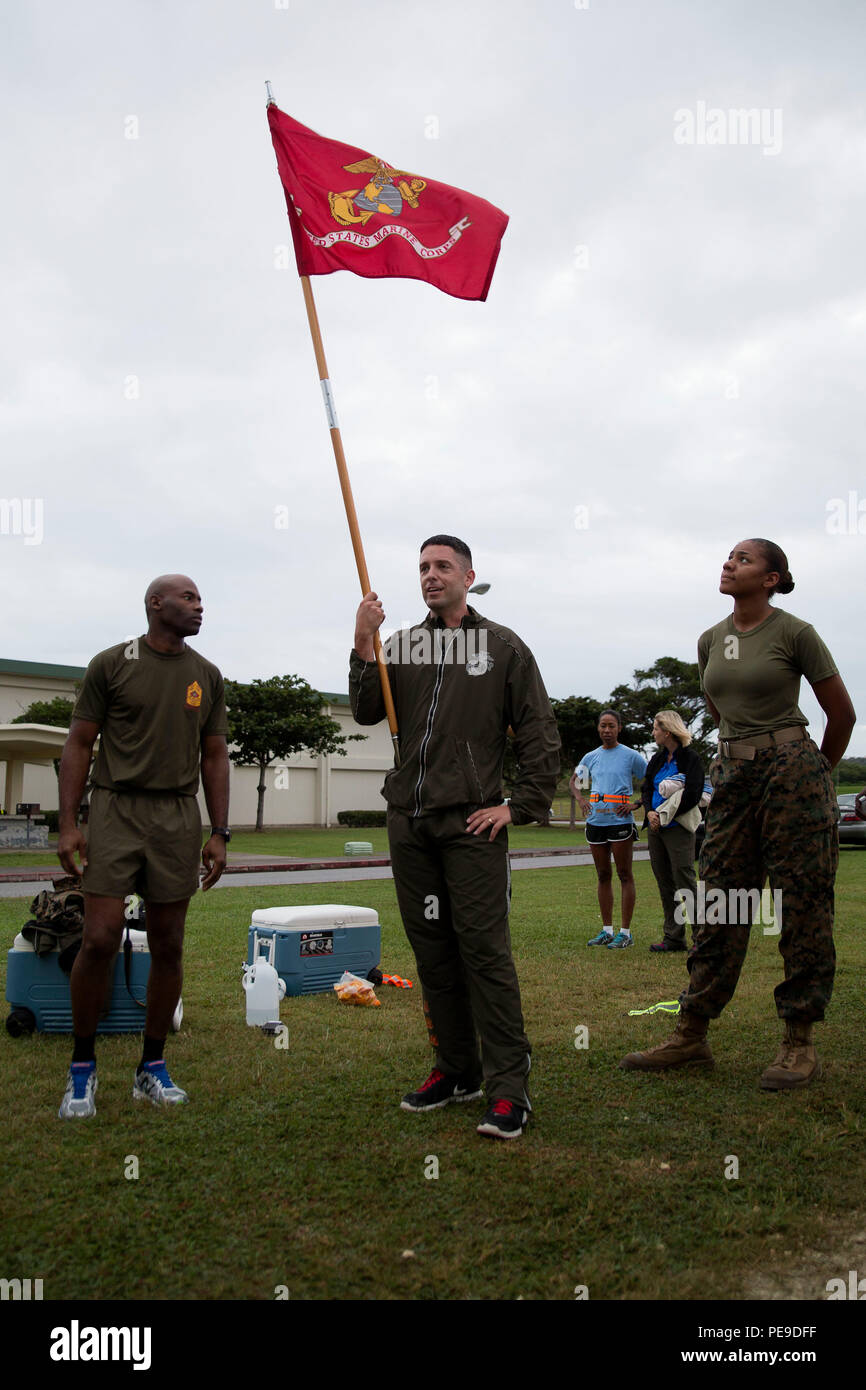 Master Sgt. Jason Annis holds the guidon as he congratulates Marines on finishing 240 laps at the Semper Fit track Nov. 10 on Marine Corps Air Station Futenma, Okinawa, Japan. The Marines ran the laps to celebrate the 240th Marine Corps Birthday. It took the Marines over seven hours to finish. Annis is the communications chief for MCAS Futenma S-6, Communications, Marine Corps Installations Pacific. Stock Photo