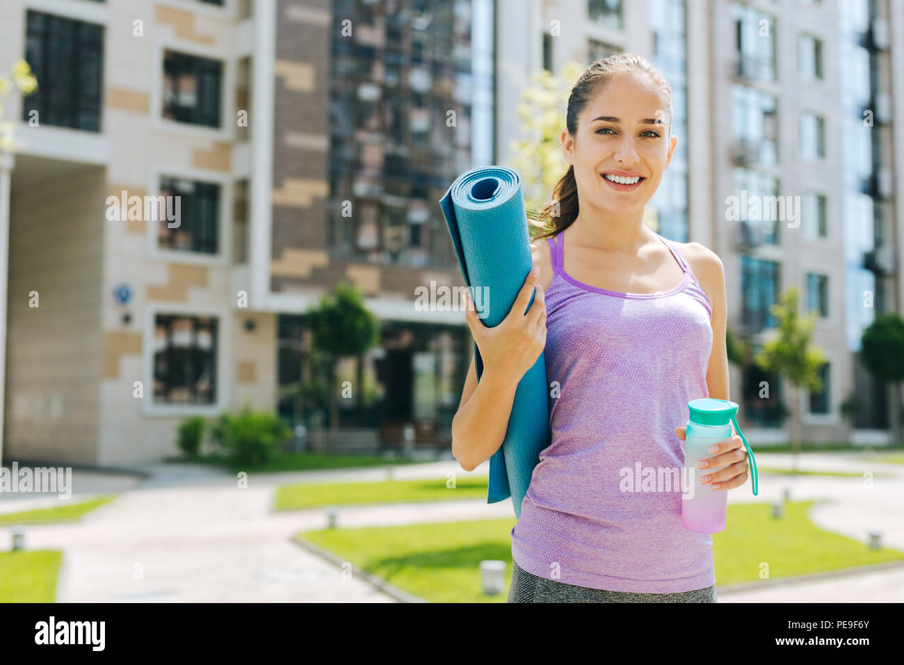 Delighted young woman carrying a yoga mat Stock Photo Alamy