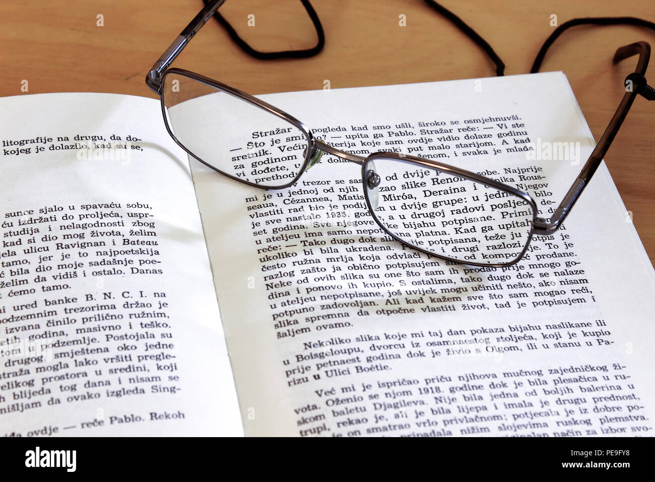 Reading glasses laying on an open book page Stock Photo - Alamy