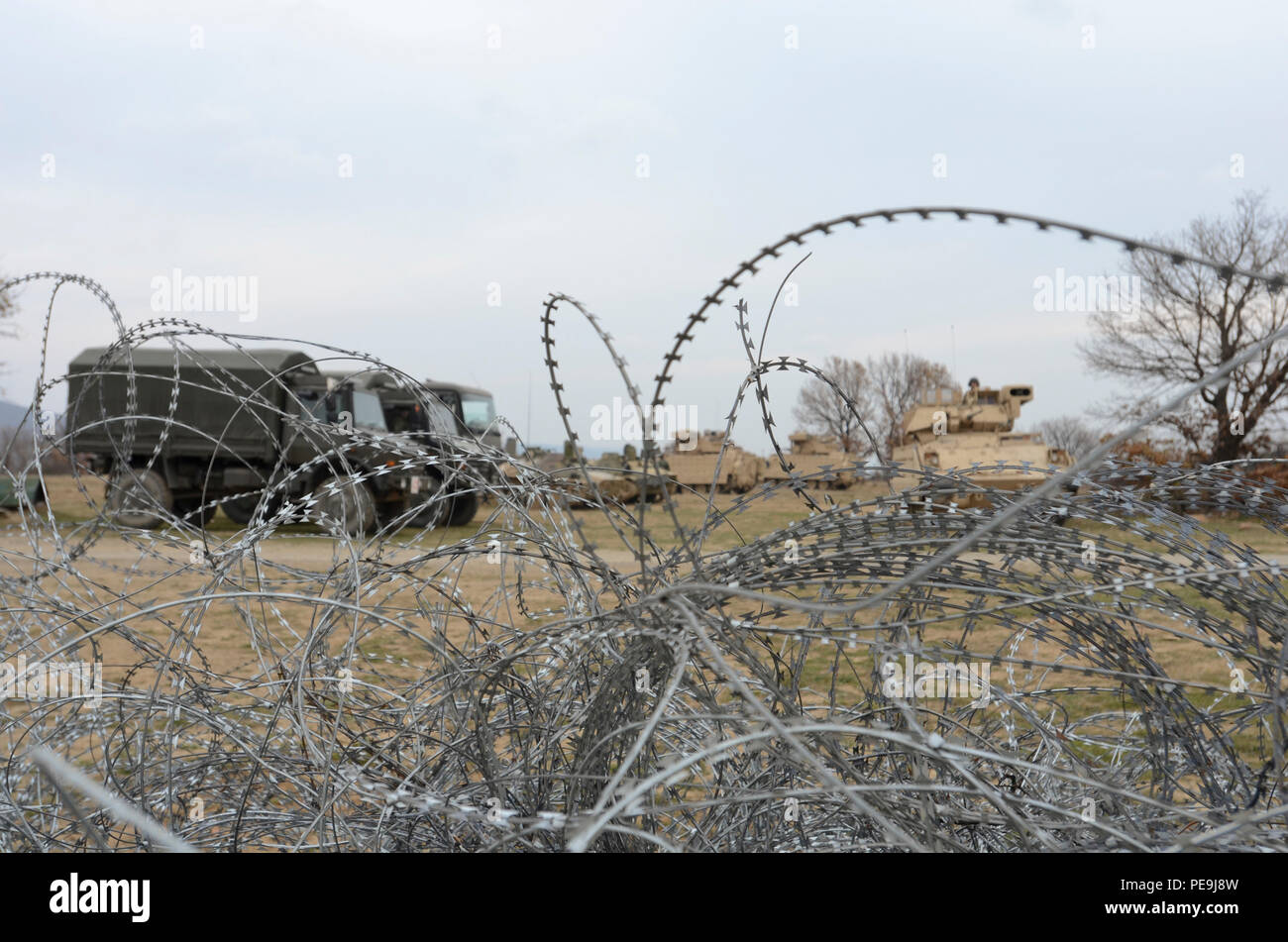 Bulgarian and U.S. Army vehicles park in the open field on the other side of the pile of tangled