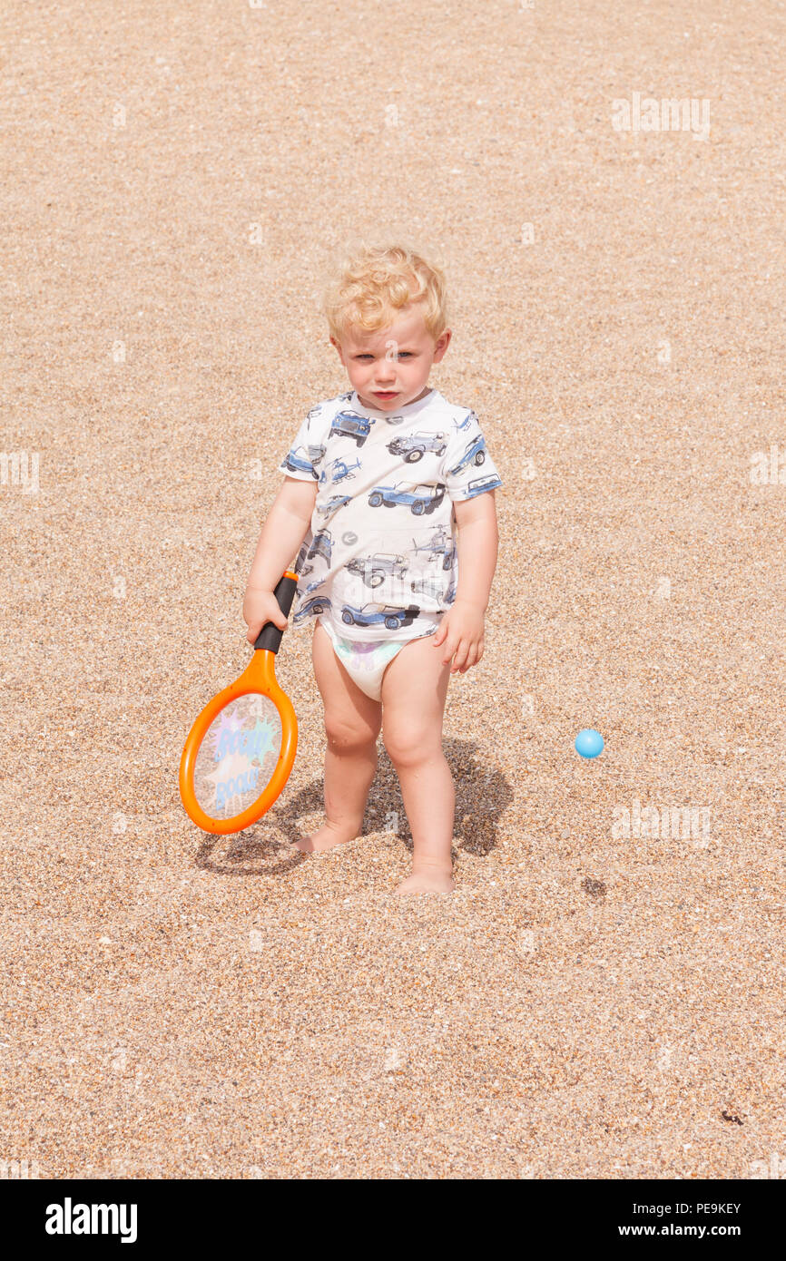 Two year old bow playing with a bat and ball, Devon, England, United Kingdom. Stock Photo