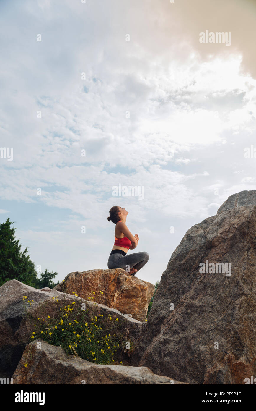 Dark-haired woman looking up into the sky while doing yoga Stock Photo