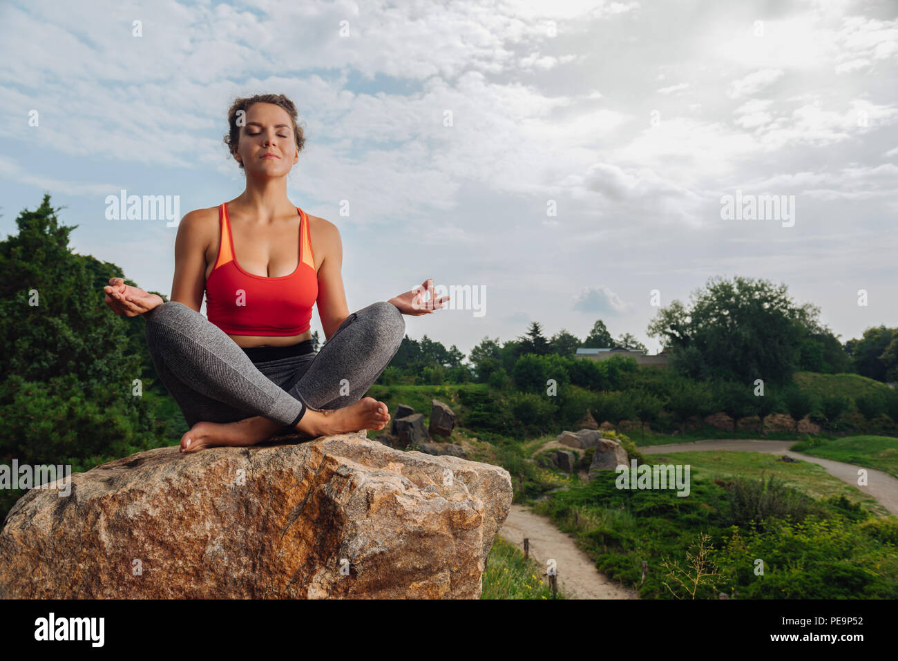 Dark-haired woman sitting and meditating while having vacation Stock Photo