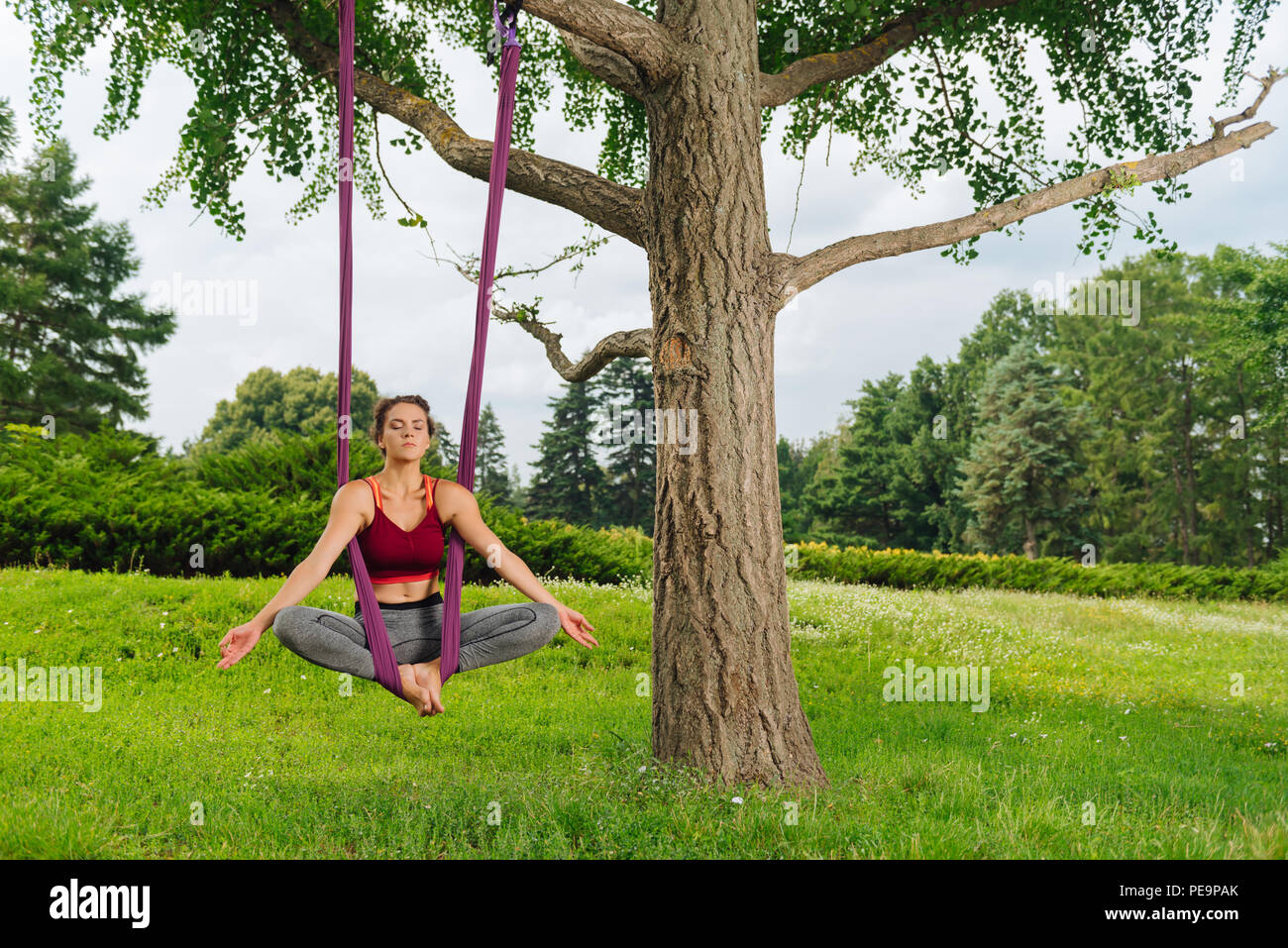Professional yoga woman performing sitting aerial yoga pose Stock Photo
