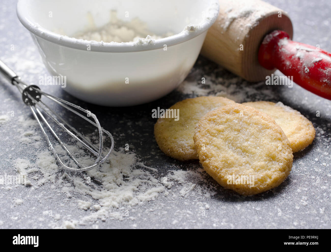 Crisp sugar cookies are surrounded by flour and cooking utensils on