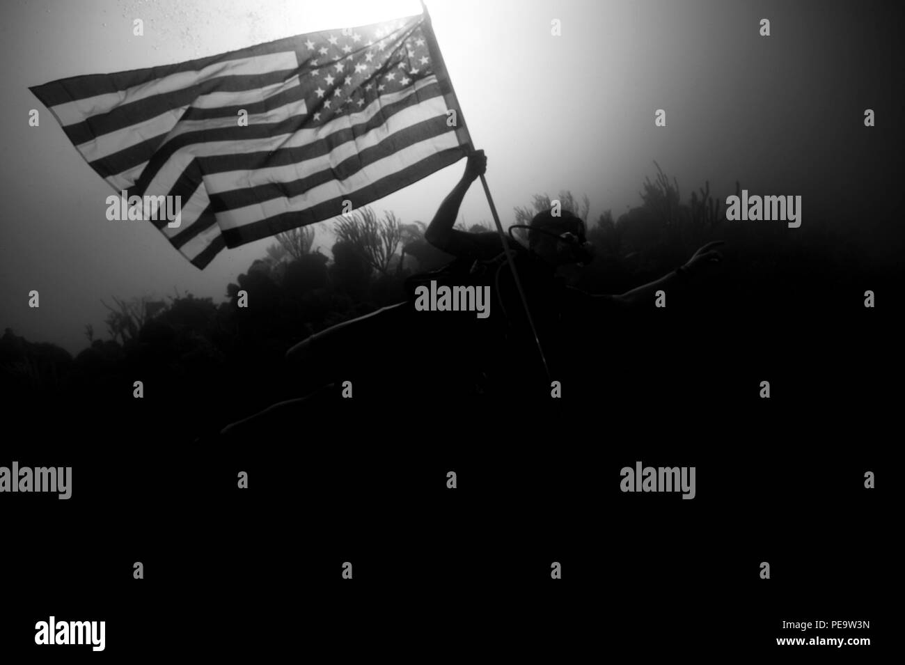 151118-N-QA919-108 Guantanamo Bay, Cuba. (Nov. 18, 2015) - Mass Communication Specialist 1st Class Blake Midnight, assigned to Expeditionary Combat Camera, flies the American Flag underwater off the coast of Guantanamo Bay, Cuba, Nov. 18, 2015. Expeditionary Combat Camera's Underwater Photo Team conducts annual training to hone its divers specialized skill set and ensure valuable support of Department of Defense activities worldwide. (U.S. Navy photo by Mass Communication Specialist 2nd Class Tyler N. Thompson) Stock Photo