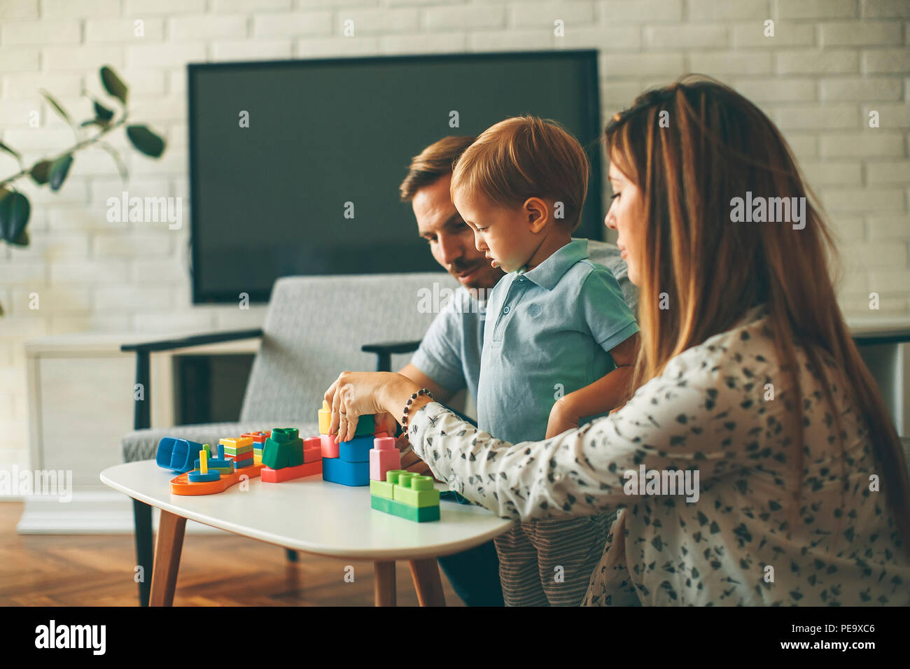 Little boy playing toys with mother and father at modern home Stock ...