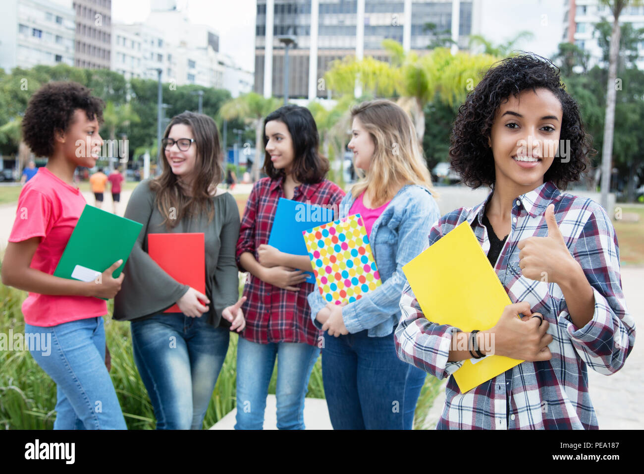 Successful latin american female student with group of international students outdoors on campus of university Stock Photo