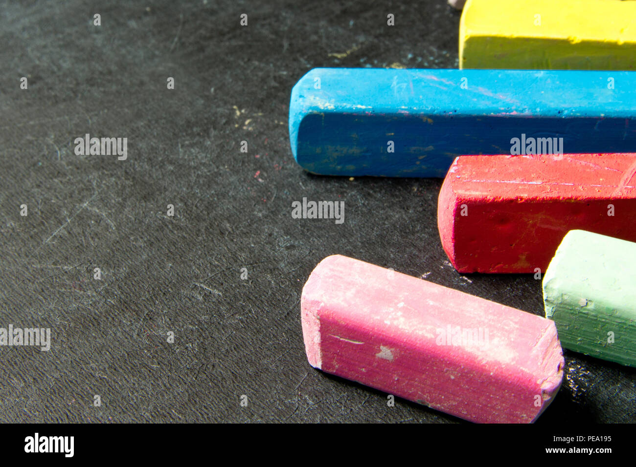 Dark chalkboard with colored crayons for drawing. Copy space Stock