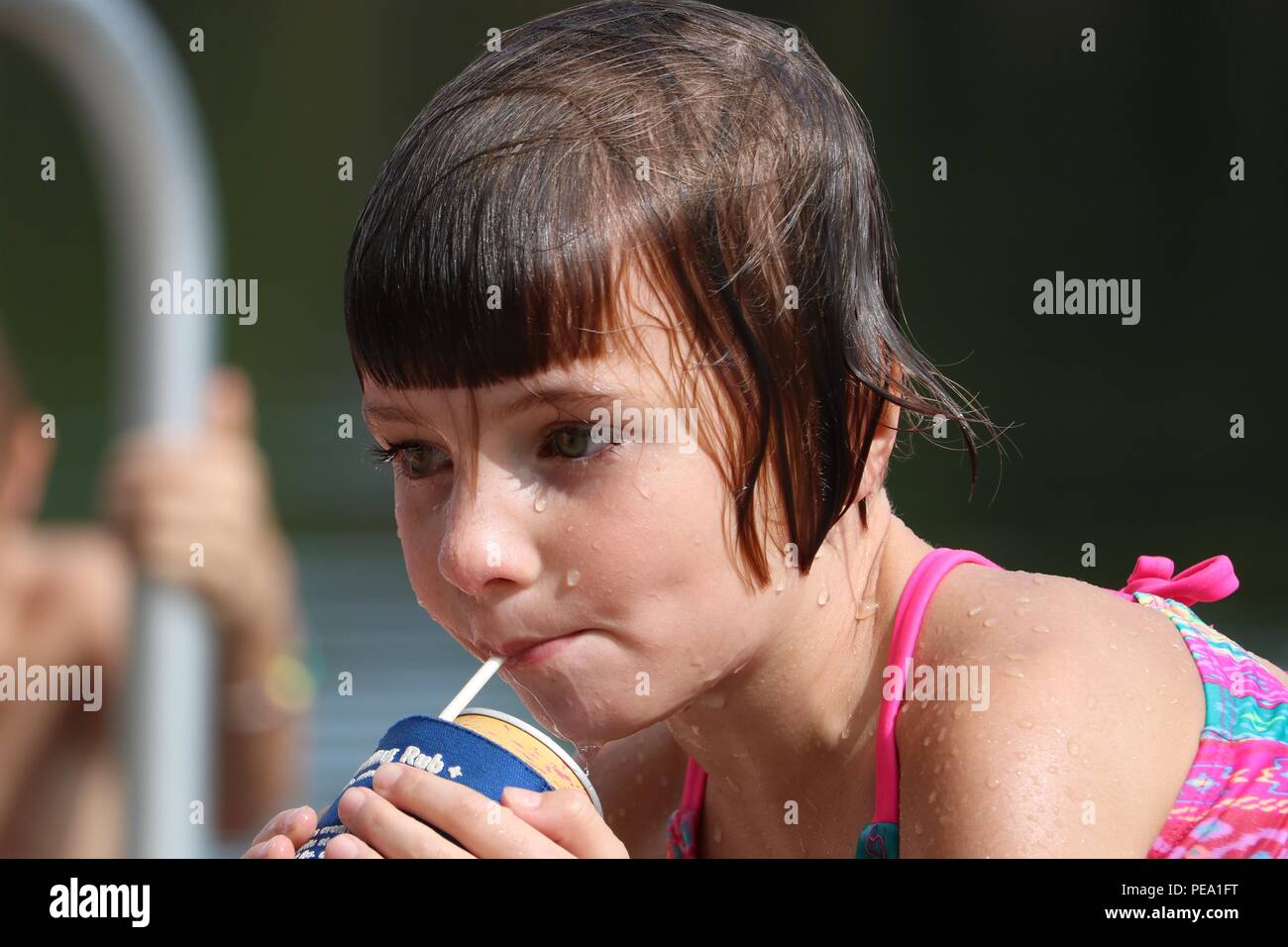 Wet young child having a drink while taking a break from swimming Stock Photo
