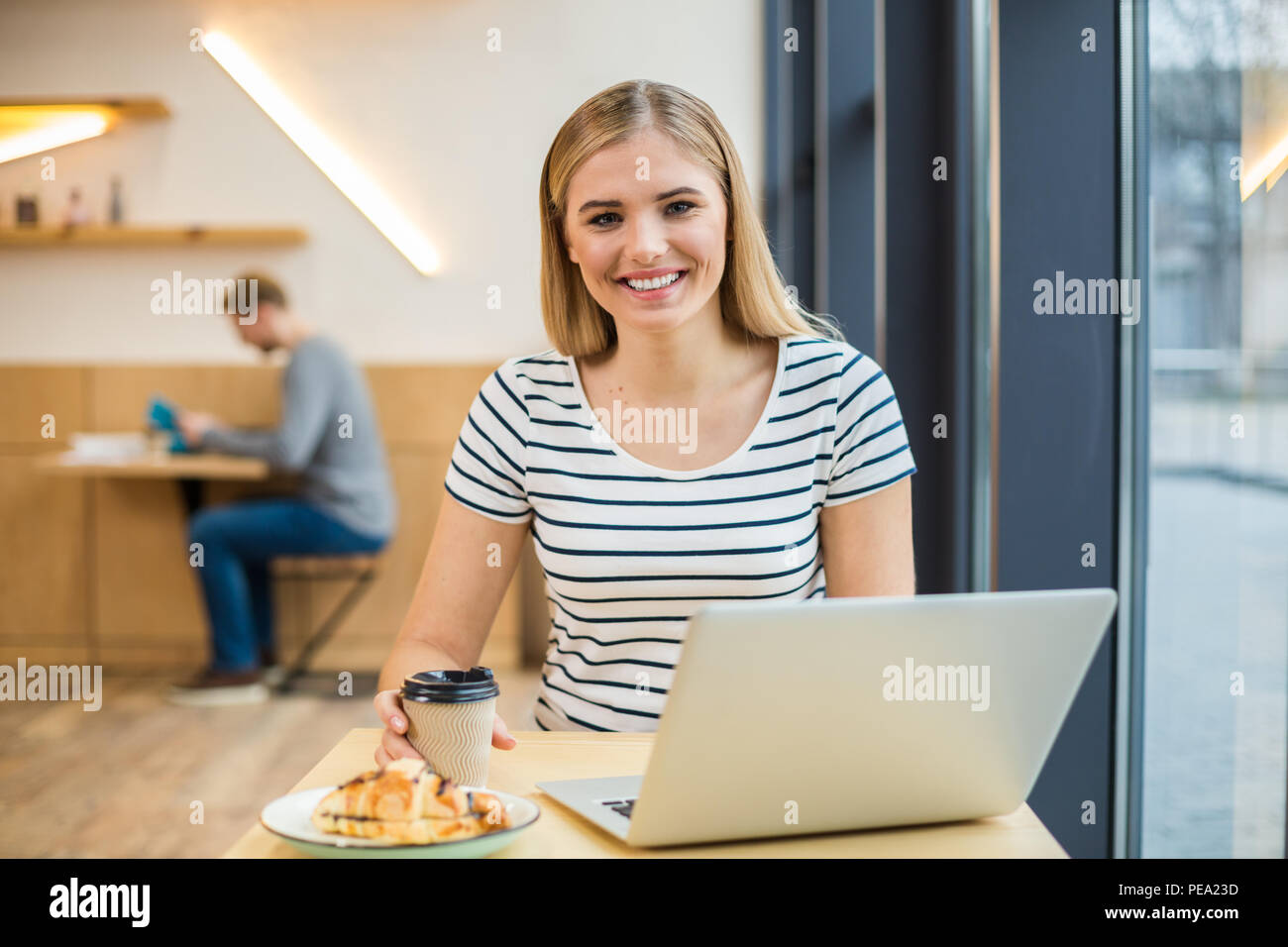 Energizing drink. Happy delighted positive woman sitting at the table and having coffee while enjoying her drink Stock Photo