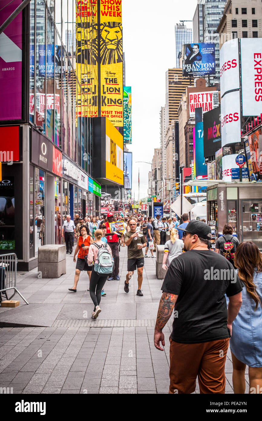 NEW YORK CITY - JULY 26, 2018: Busy sidewalk in Times Square in Manhattan crowded with many people walking and billboards. Stock Photo