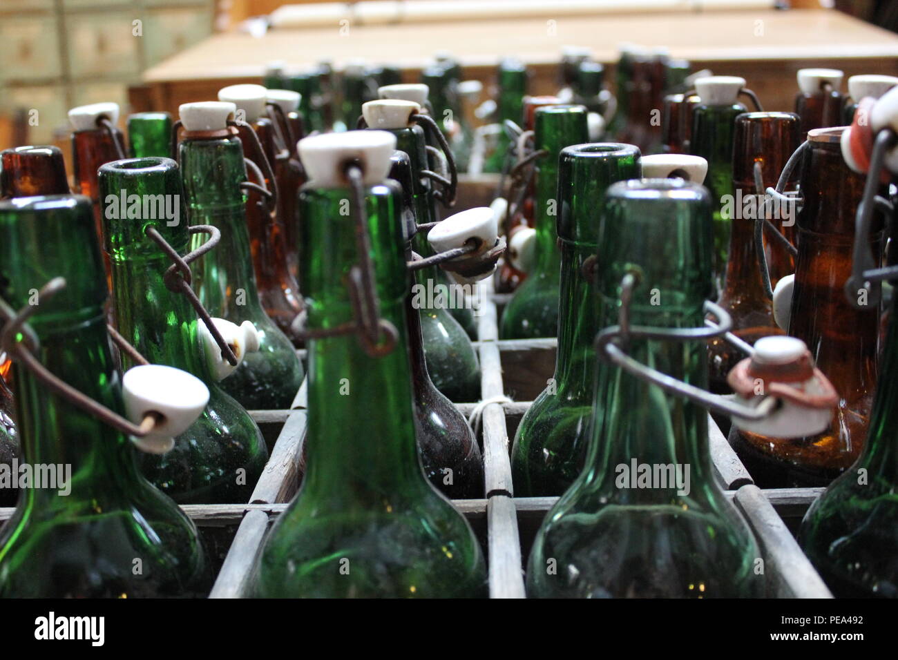 Wooden box of vintage green glass bottles with plastic caps at