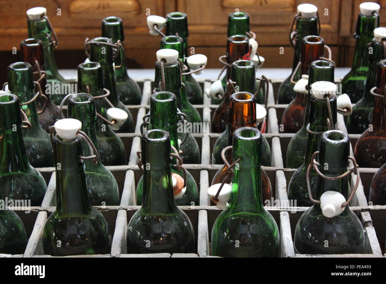 Wooden box of vintage green glass bottles with plastic caps at