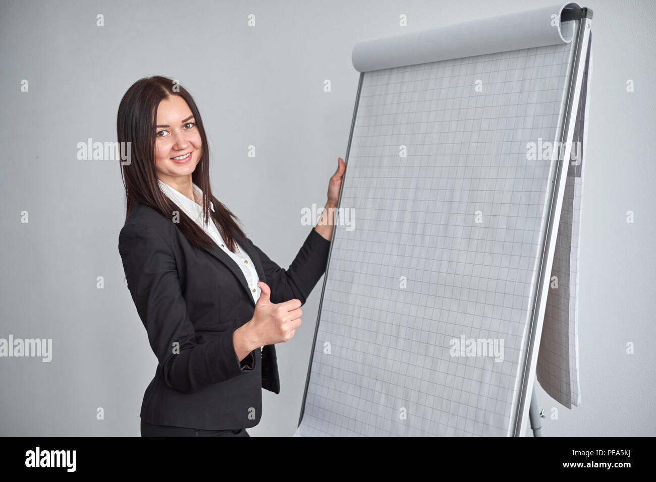 Portrait of young smiling businesswoman standing by flipchart in office Stock Photo