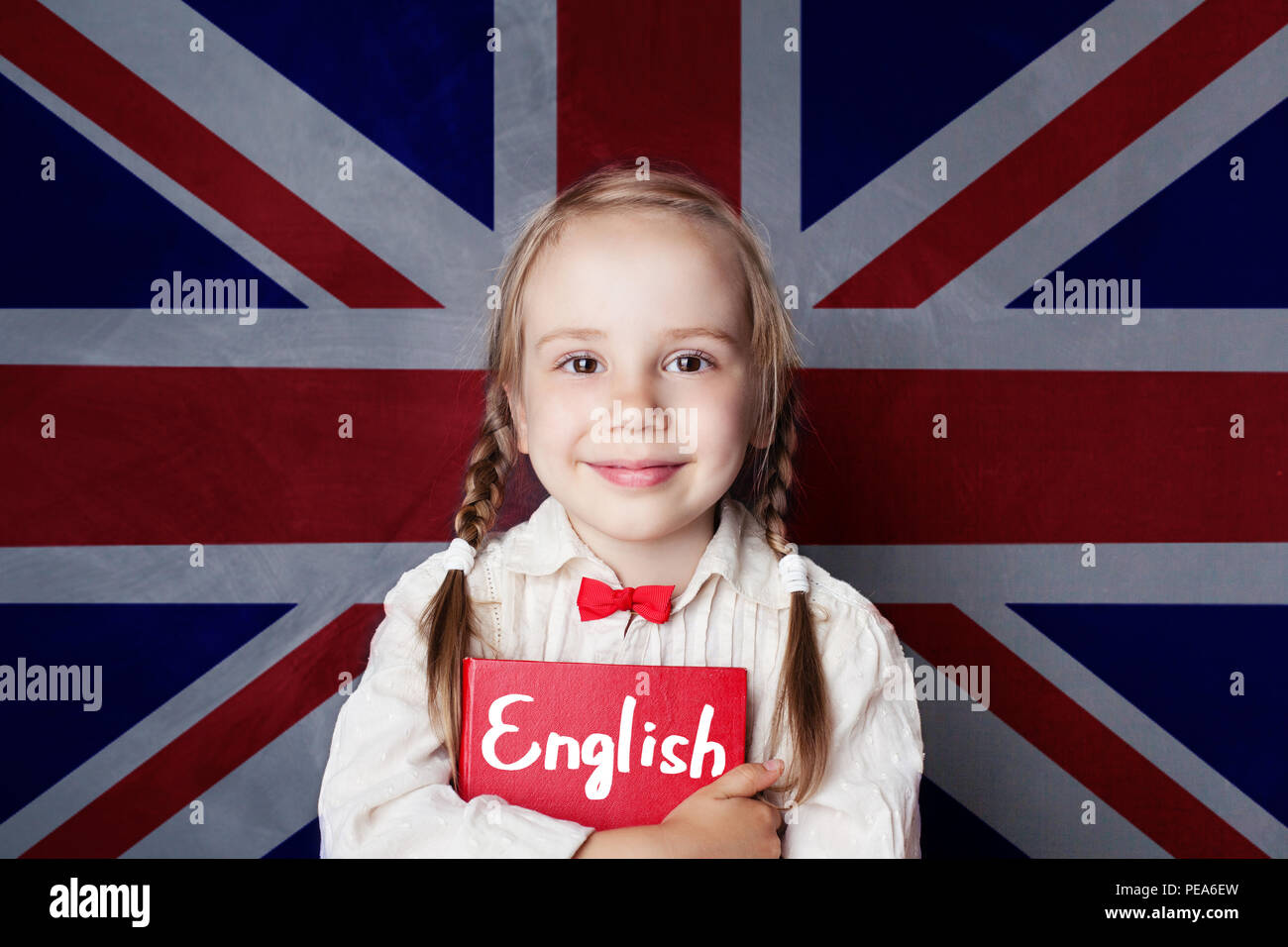English concept with little girl student with book against the UK flag