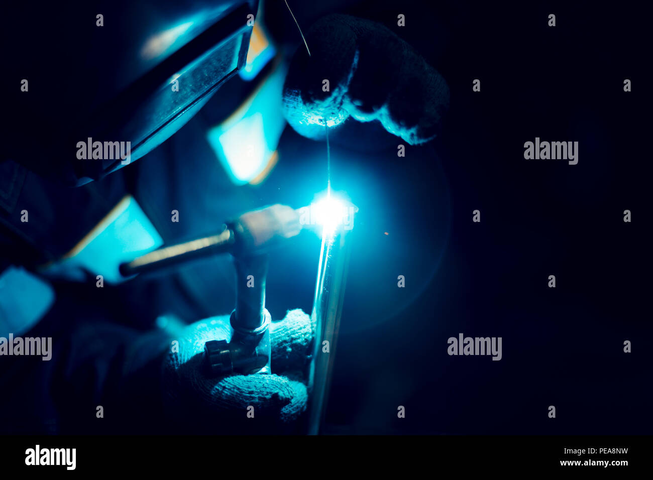 The welder lights the arc and begins to weld the metal structure of stainless steel Stock Photo