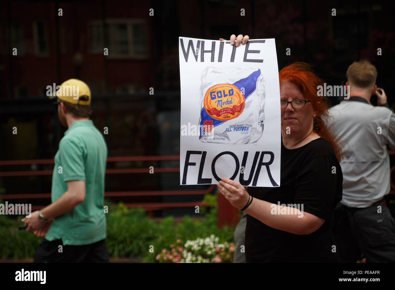 Washington, United States. 12th Aug, 2018. A protestor faces her sign toward white supremacists, escorted by police, who are making their way from Foggy Bottom Metro station to Lafayette Park for a Unite the Right event commemtorating the one-year anniversary of the deadly rally in Charlottesville. Credit: Michael Candelori/Pacific Press/Alamy Live News Stock Photo