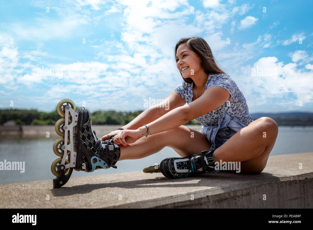 A beautiful smiling Filipino girl having happy time during the roller blanding and enjoying on the city rivershore on a beautiful summer day. Stock Photo