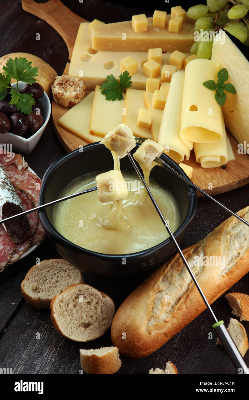 bewaker Assimilatie Mens Gourmet Swiss fondue dinner on a winter evening with assorted cheeses on a  board alongside a heated pot of cheese fondue with two forks dipping bread  Stock Photo - Alamy