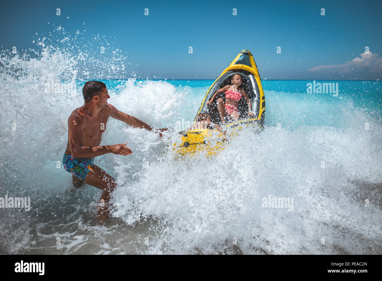 Happy family is enjoying floating in yellow kayak at tropical ocean