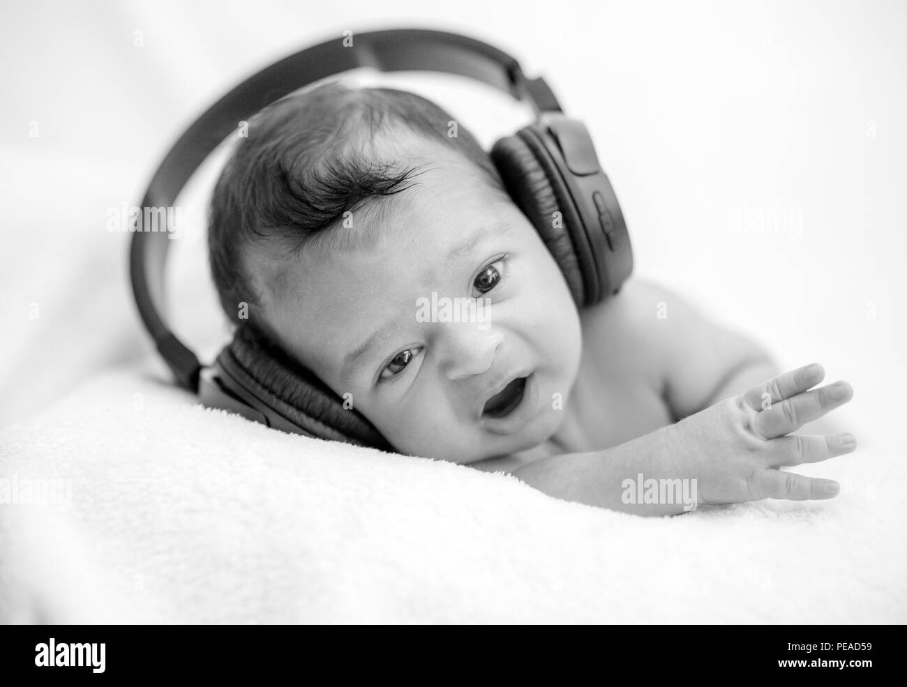 Cute newborn baby hearing music with headphones on a blanket happy
