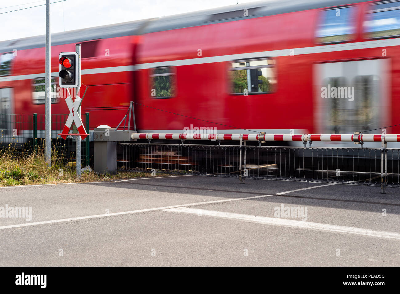 A passenger train passing through a guarded railway crossing with