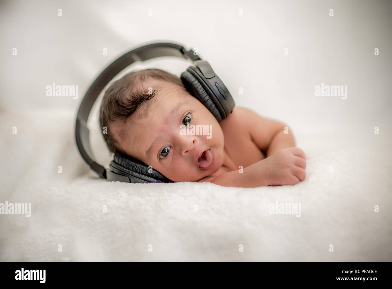 Cute newborn baby hearing music with headphones on a blanket
